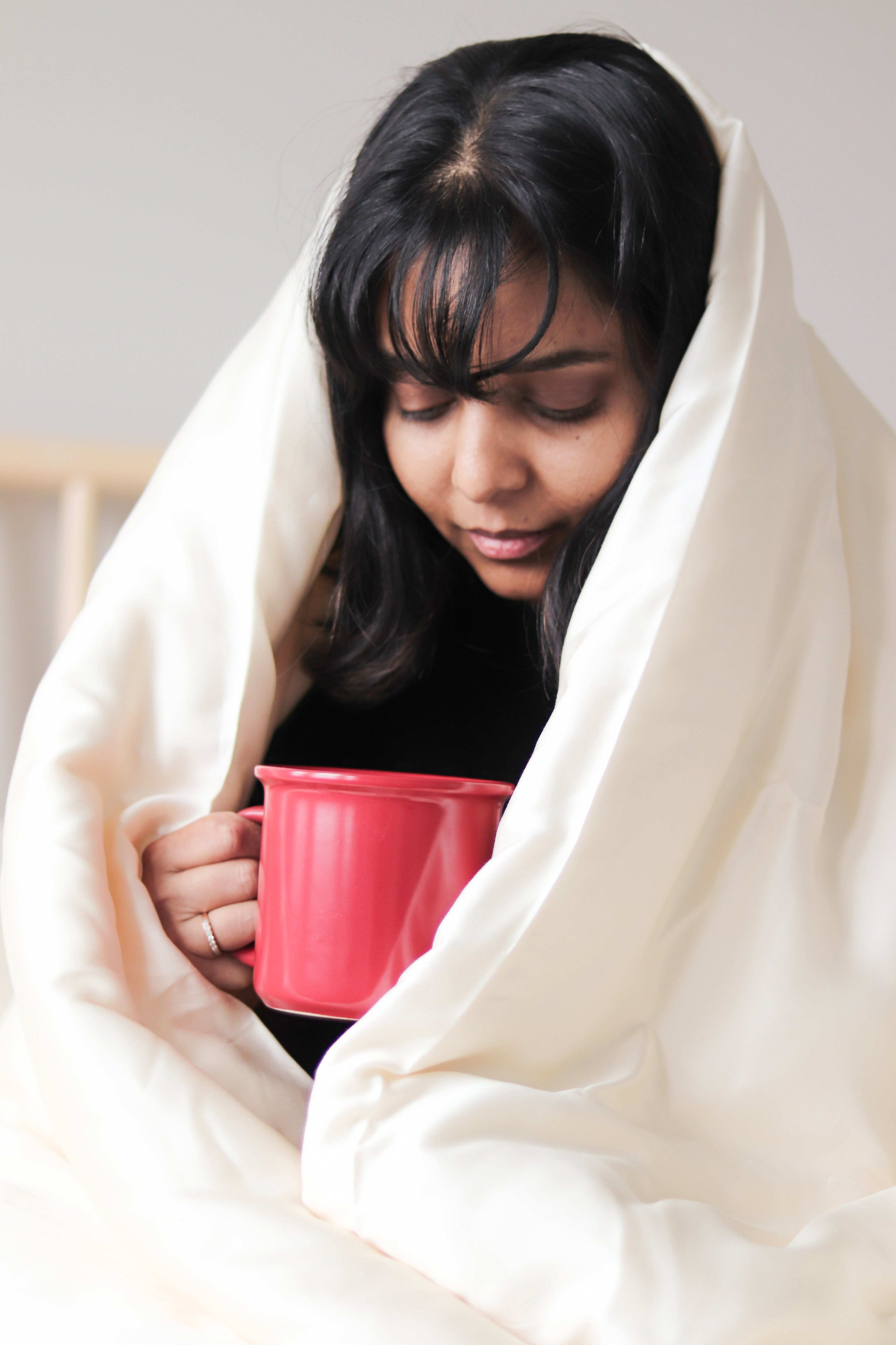 A person on a bed with silky smooth, hypoallergenic Tencel sheets, designed to reduce skin irritation, wick away moisture, and provide a breathable, eco-conscious sleep environment. Ideal for sensitive skin and a restful night.